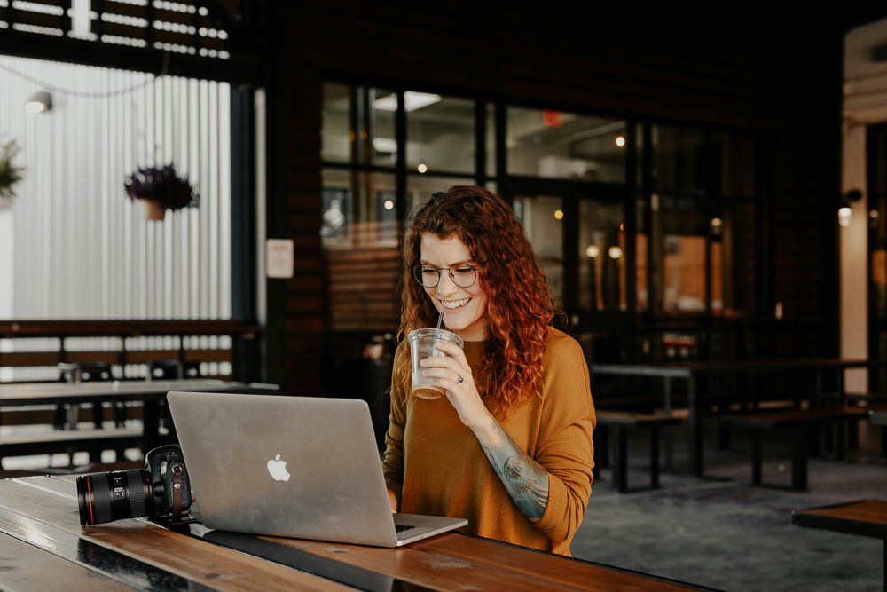 Female entrepreneurs evaluating professional website design services, enjoying iced coffee.