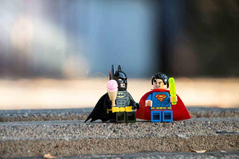 Lego versions of iconic heroes illustrate the decision between local or remote web design and graphic design solutions.